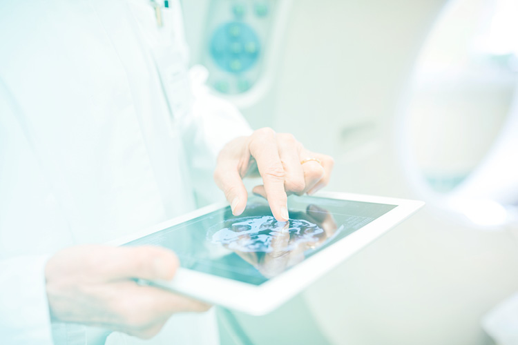 Medizinisches Personal hält Tablet mit medizinischen Bilddaten in der Hand